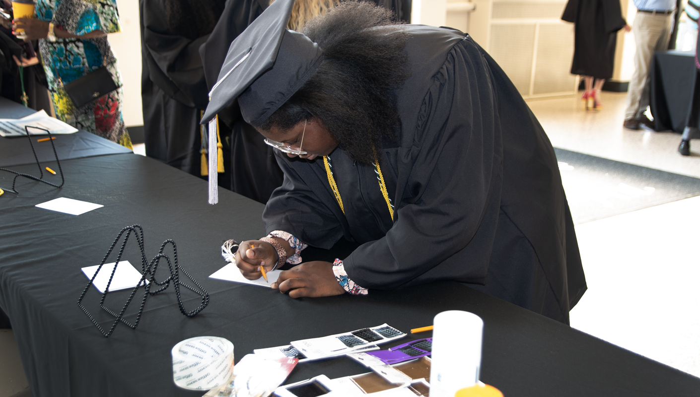 A graduate writing their name on an index card