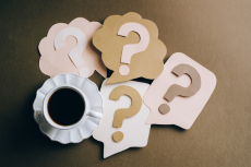 Coffee cup surrounded by question marks