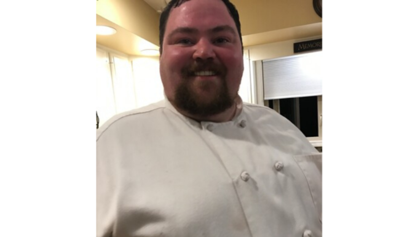 Pictured is Barrett Fuller in a chef suit, smiling. 