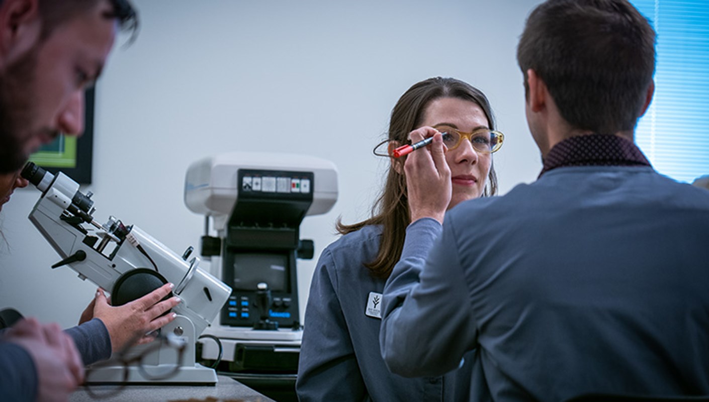 An Optician student checking a fellow classmate's eyes